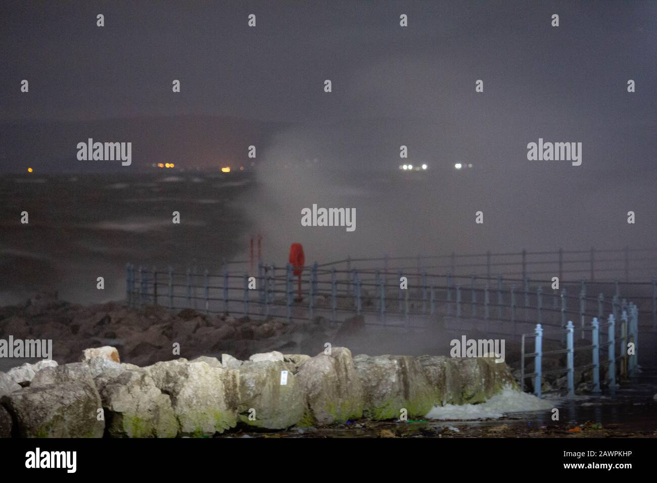 Grosvenor Break Water, Heysham, Lancashire, Großbritannien. Februar 2020. Heysham Hightidde heute Abend hat mehr Wellen über die Spitze des Breakwater mit He Lights of Ulverston im Hintergrund Credit gebracht: Photographing North/Alamy Live News Stockfoto