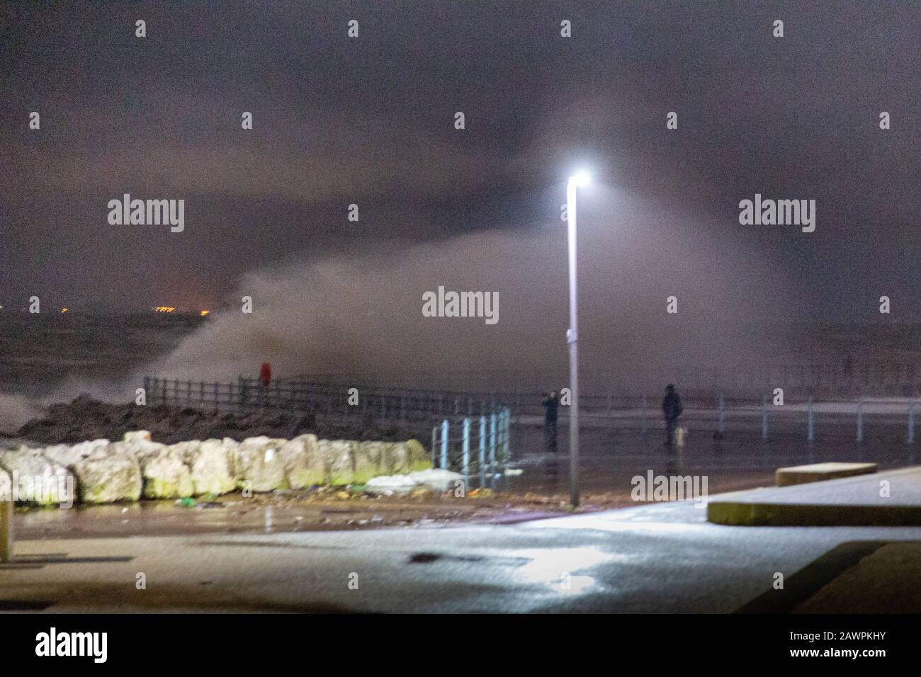 Grosvenor Break Water, Heysham, Lancashire, Großbritannien. Februar 2020. Heysham Hightidde heute Abend hat mehr Wellen über die Spitze des Breakwater mit He Lights of Ulverston im Hintergrund Credit gebracht: Photographing North/Alamy Live News Stockfoto