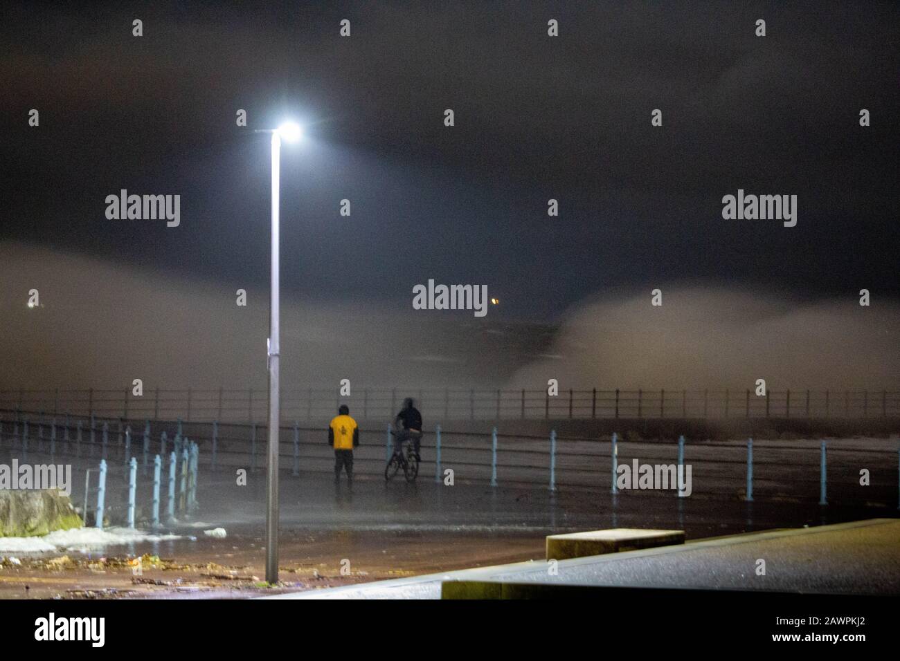 Grosvenor Break Water, Heysham, Lancashire, Großbritannien. Februar 2020. Heysham Hightidde heute Abend hat mehr Wellen über die Spitze des Breakwater mit He Lights of Ulverston im Hintergrund Credit gebracht: Photographing North/Alamy Live News Stockfoto