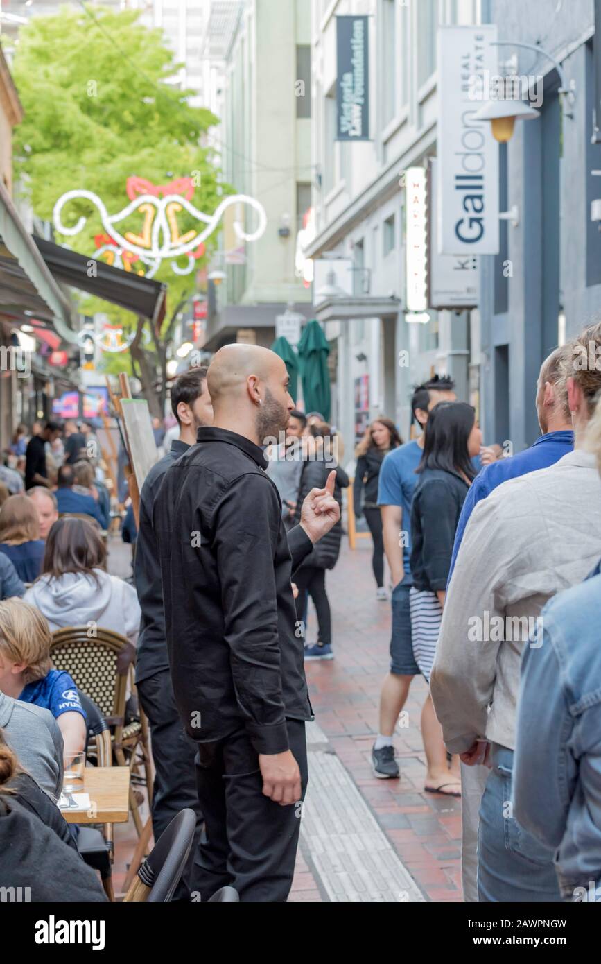 Zwei Gäste vor einem Restaurant in der Hardware Lane, eines von vielen Restaurants, die eine Straße in der Innenstadt von Melbourne, Australien, füllen Stockfoto