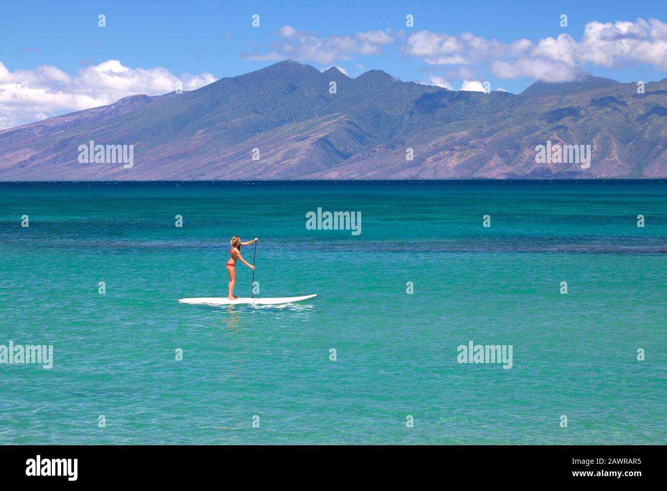 Fit, gesunde Frau paddelt ein Stehpaddelbrett in Napili Bay, Maui, Hawaii. Molokai in der Ferne. Stockfoto