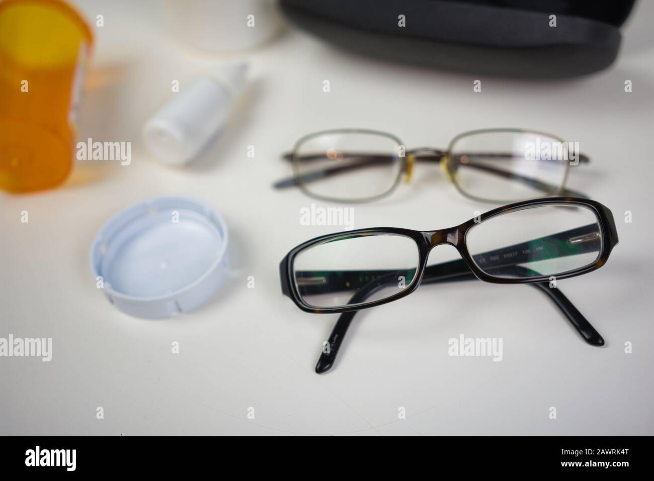 Brille auf weißem Counter mit verschiedenen Augenpflegeprodukten. Flaches Lay von medizinischem Zubehör für die Sehpflege Stockfoto