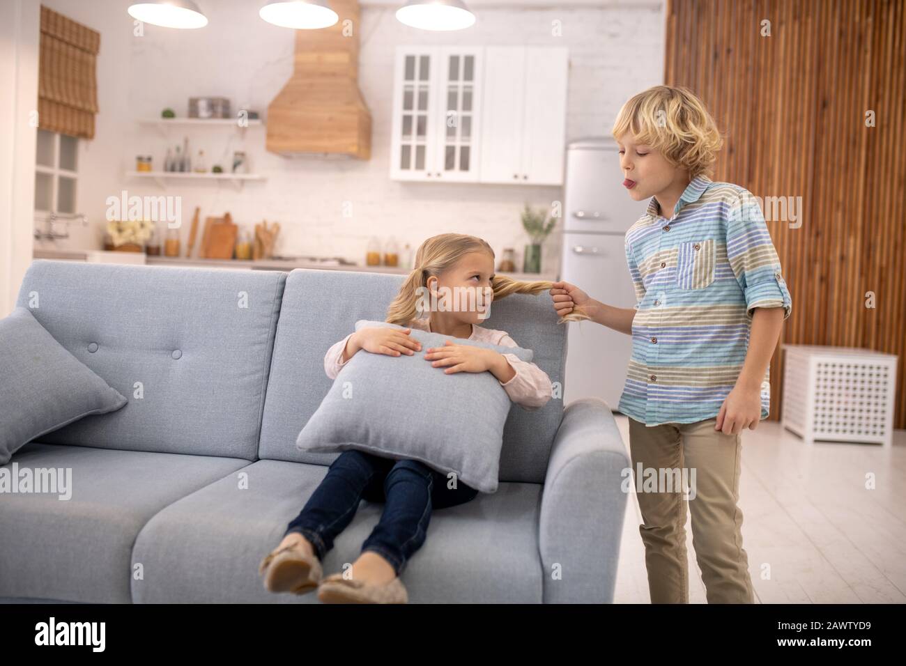 Junge ziehen Mädchen Pferdeschwanz und setzen seine Zunge heraus Stockfoto