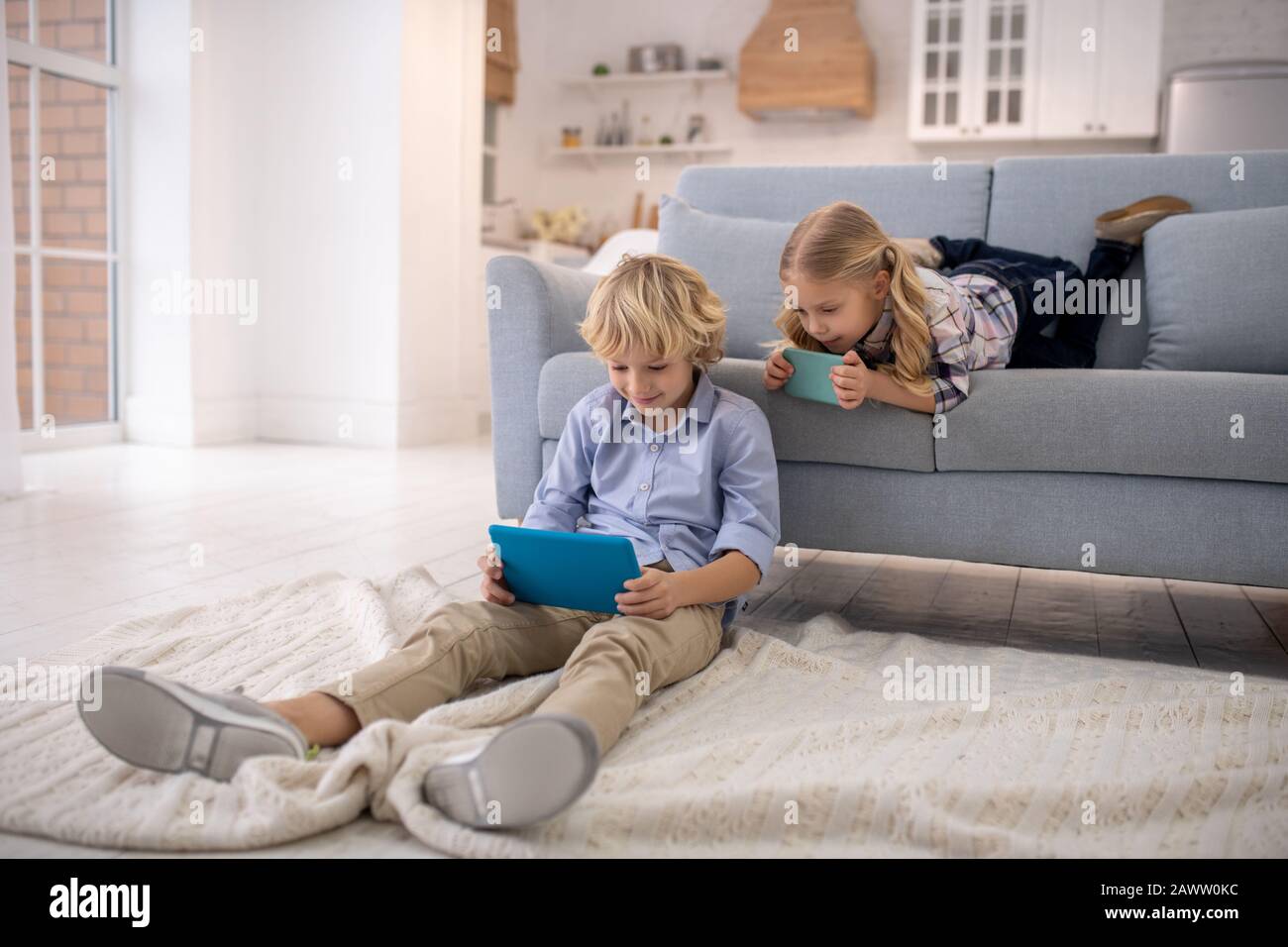 Junge auf dem Boden sitzend, Mädchen auf Sofa liegend Stockfoto