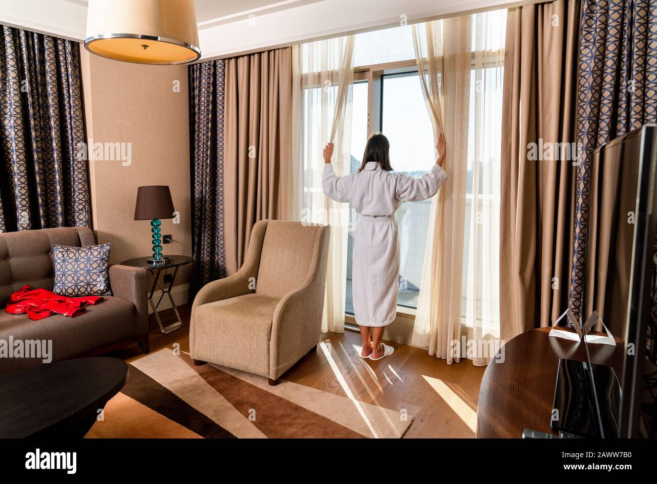 Schöne Frau blickt aus dem Fenster in ihrem modern eingerichteten Zimmer Stockfoto Schöne Frau blickt aus dem Fenster in ihrem modern eingerichteten Zimmer Stockfoto