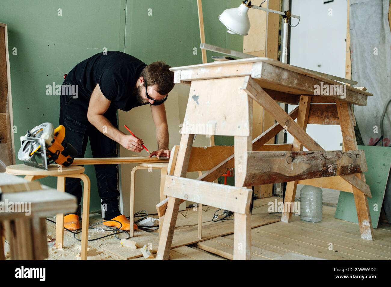 Bärtiger Mann macht Spuren auf einer Planke. Er arbeitet an der Renovierung seiner Wohnung. Stockfoto