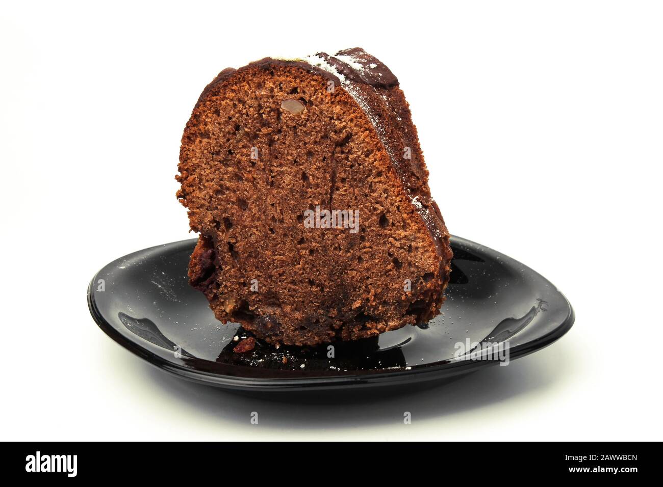Ein Stück Kuchen auf einer schwarzen Untertasse isoliert auf Weiß Stockfoto