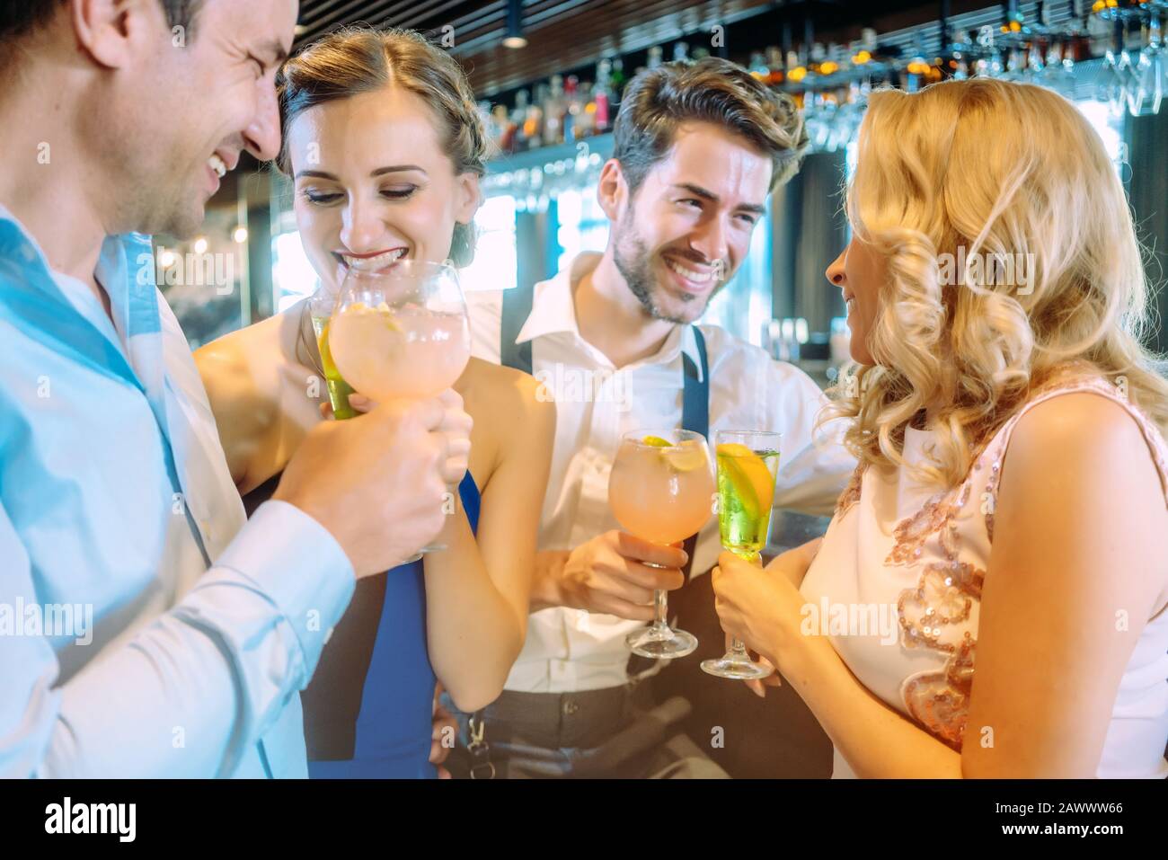 Frauen und Männer am Tresen einer Bar ihre Drinks genießen Stockfoto