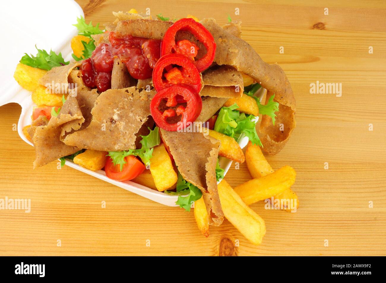 Donnern Sie kebabes Fleisch und Pommes mit Salat und Chilisauce in einem Tablett auf einem Holzhintergrund Stockfoto
