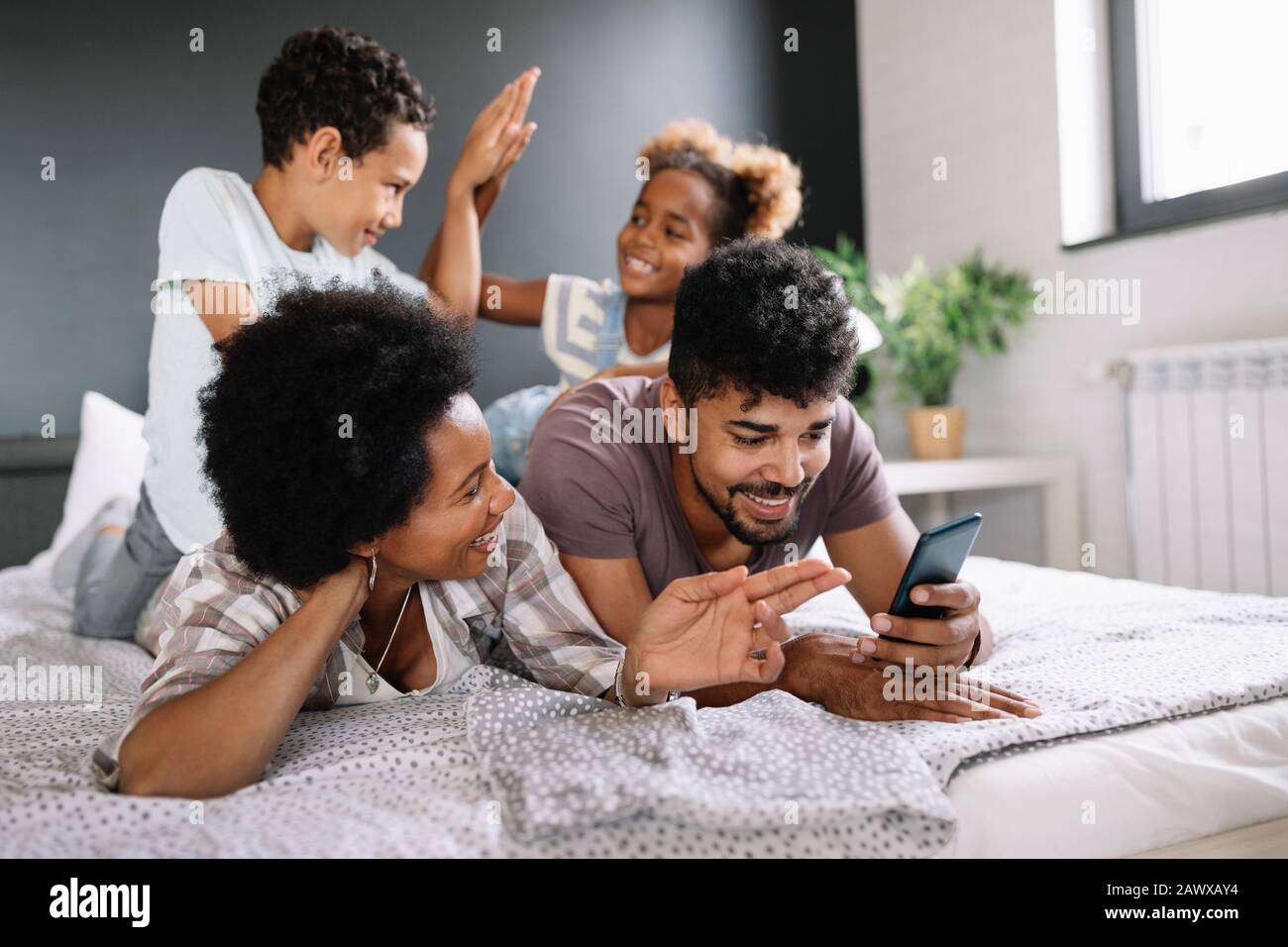 Eltern mit Kindern geniessen Sie Spiele spielen oder unterhaltsam mit mobilen Anwendungen auf dem Telefon zu Hause Stockfoto