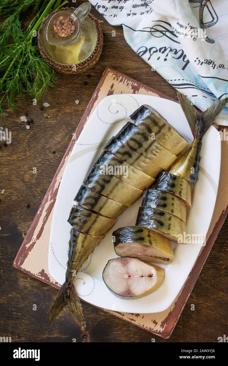 Mediterrane Küche, Fisch und Meeresfrüchte. Leckere, Appetitlich geräucherte Makrele mit Gewürzen auf dunklem rustikalem Holztisch. Flacher Laienhintergrund in der Draufsicht. Stockfoto