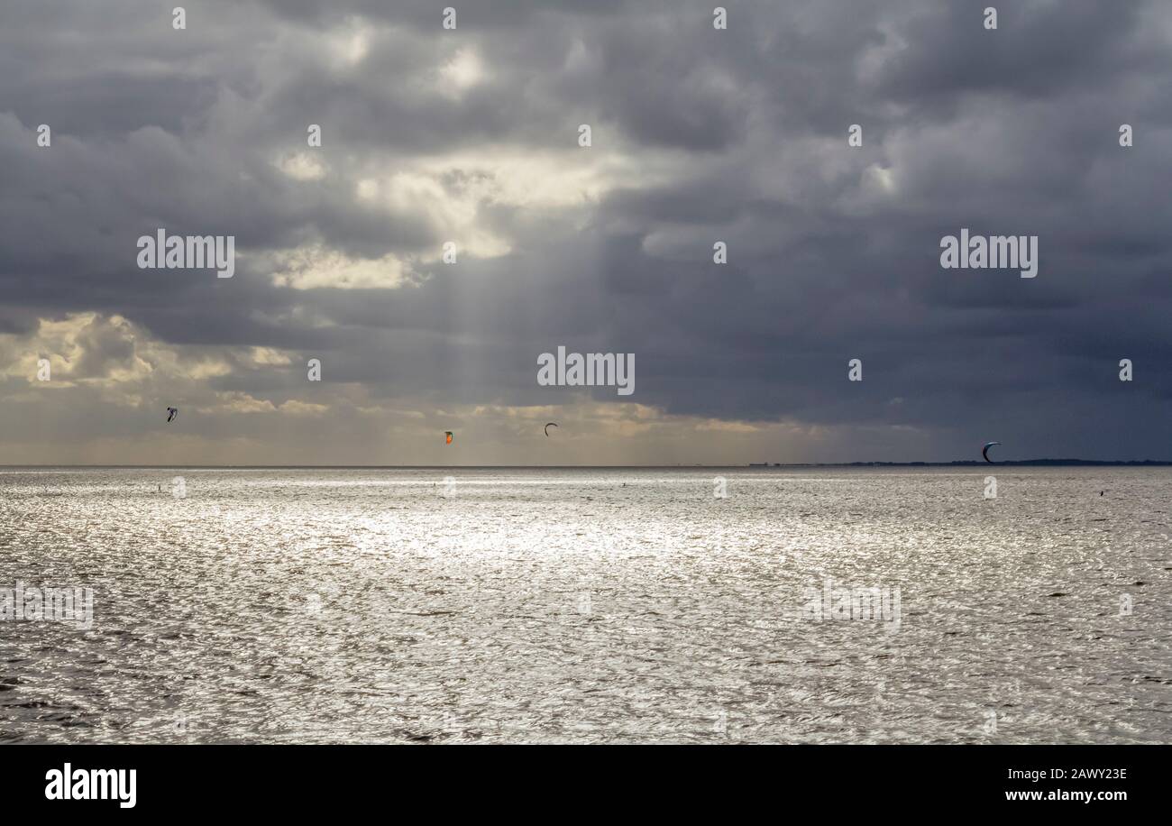 Dramatische beleuchtete Küstenlandschaft, darunter einige Kitesurfer bei Neuharlingersiel in Ostfriesland Stockfoto