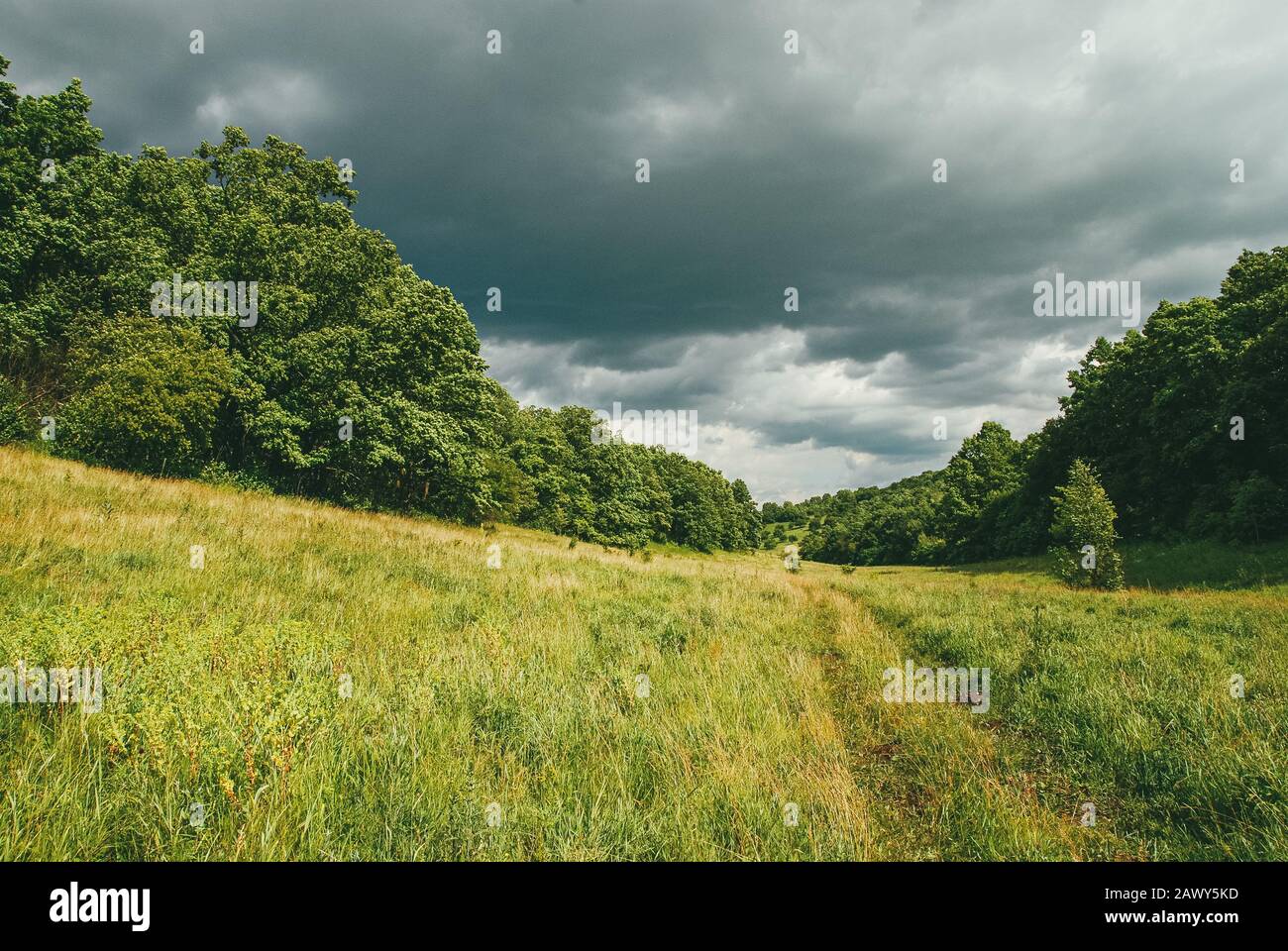 Malerische und verwinkelte Hügel mit Feldern, Straßen und dramatischen Vorstürmhimmel Stockfoto