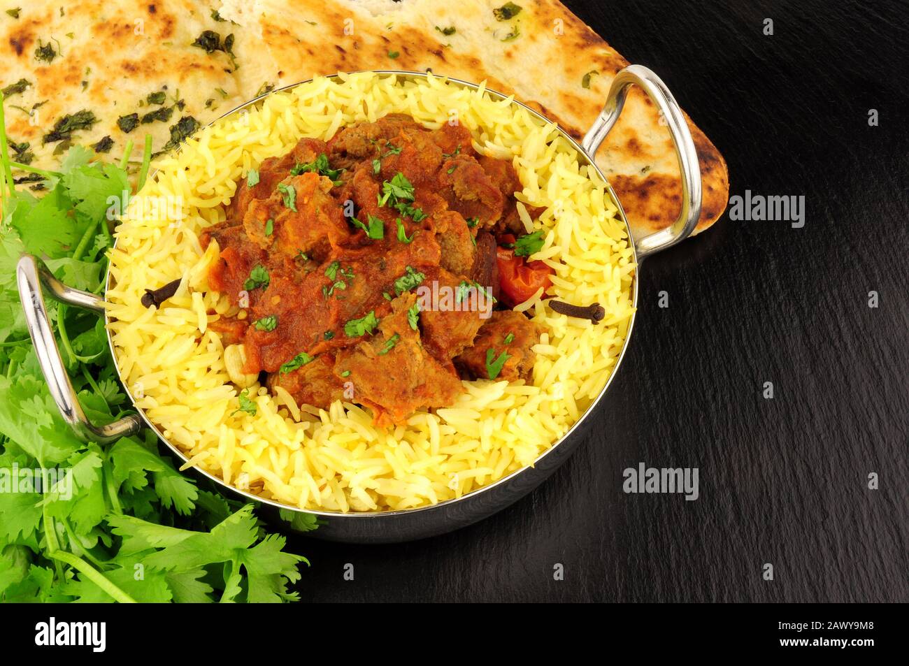 Lamb rogan josh Curry-Mahlzeit mit Pilau-Reis und naanischem Brot auf Schiefersteingrund Stockfoto