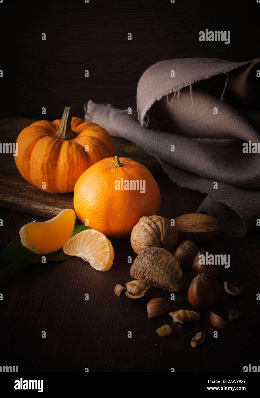 Herbststillleben mit gemischten Nüssen, Minikürbis und Orange Stockfoto