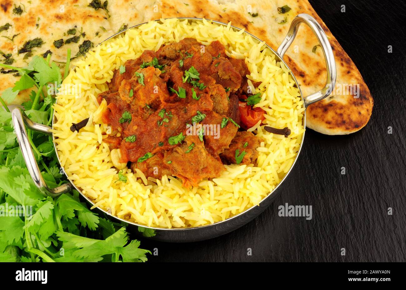 Lamb rogan josh Curry-Mahlzeit mit Pilau-Reis und naanischem Brot auf Schiefersteingrund Stockfoto
