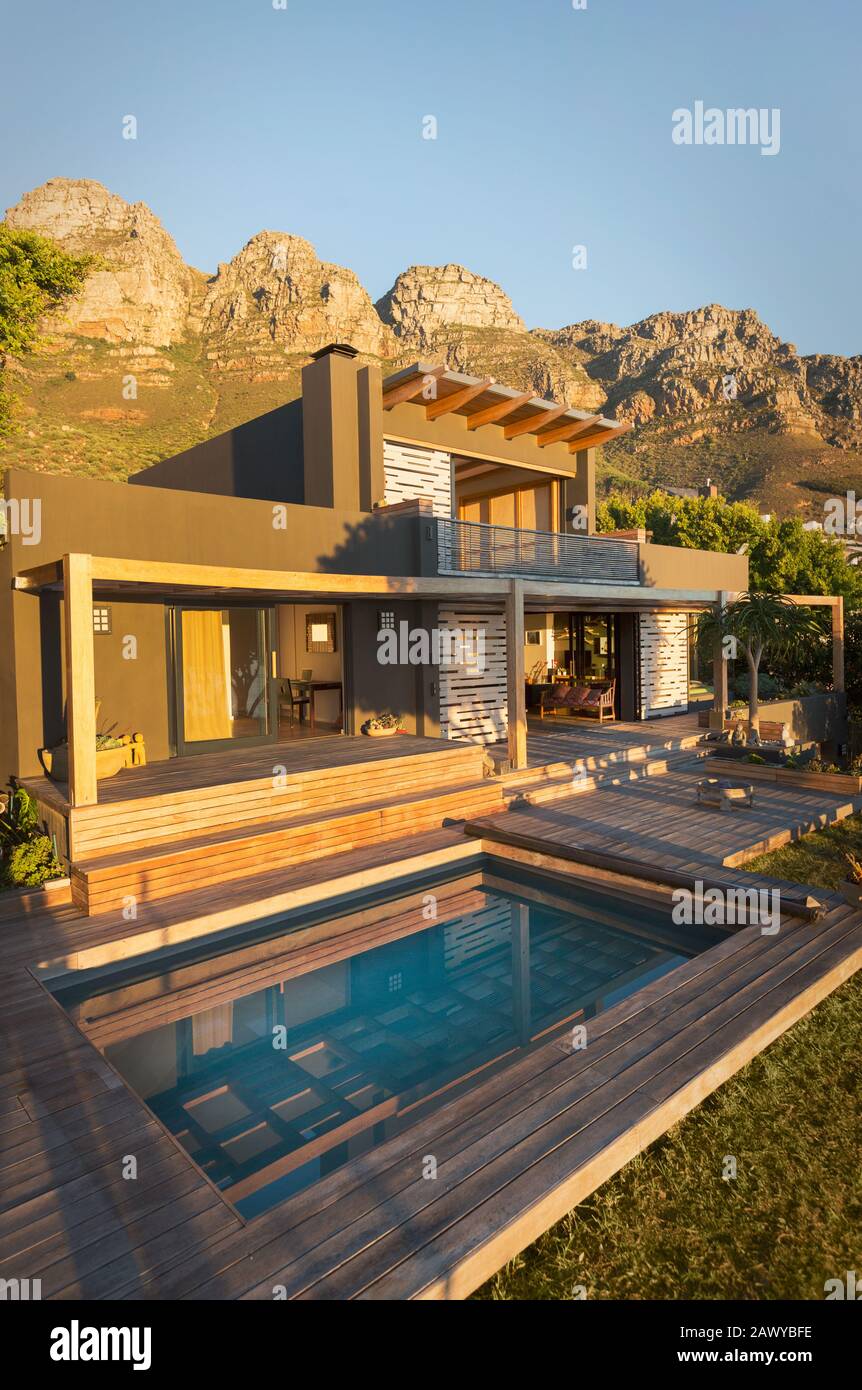 Berge hinter sonnigem Luxushaus zeigen Außenhaus mit Schwimmbad Stockfoto