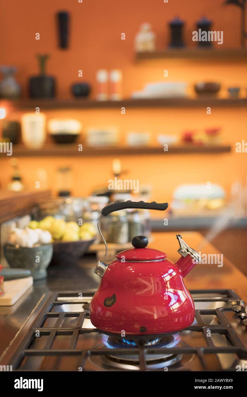 Roter Teekessel, der auf Kochplatten in der Hausküche dampft Stockfoto