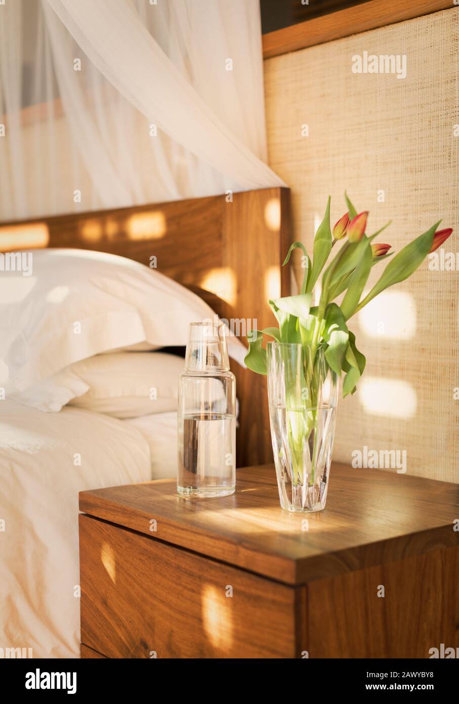 Tulpenstrauß und Wasserkrug am Nachttisch im ruhigen Schlafzimmer Stockfoto