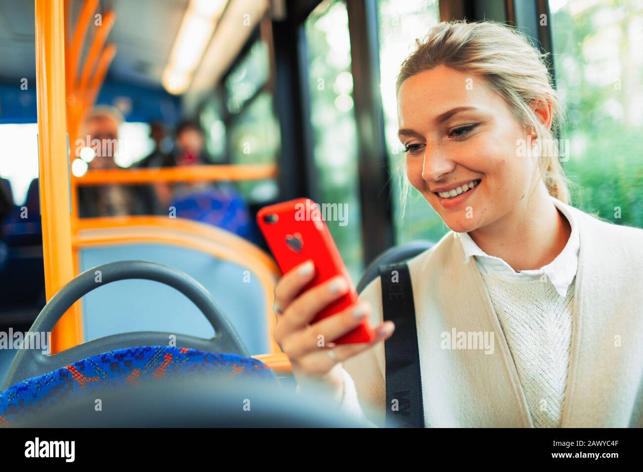 Lächelnde junge Frau mit Smartphone im Bus Stockfoto
