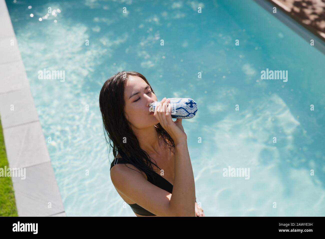Durstige Frau trinkt im sonnigen Sommer am Pool Wasser Stockfoto
