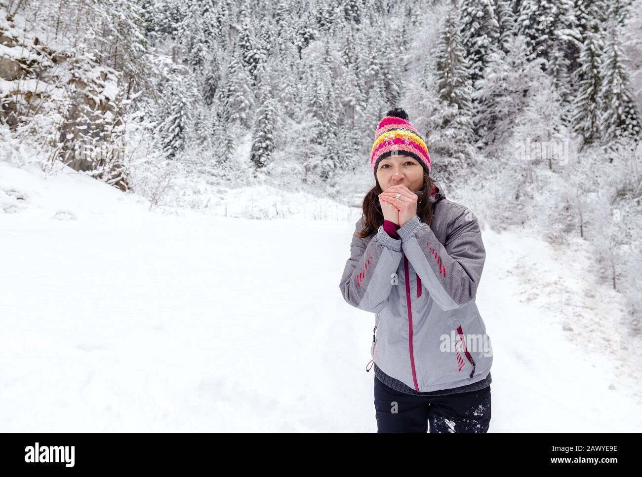 Junge Frau mit farbiger Kleidung bläst im Winter in gefrorenen Händen. Platz für Text Stockfoto
