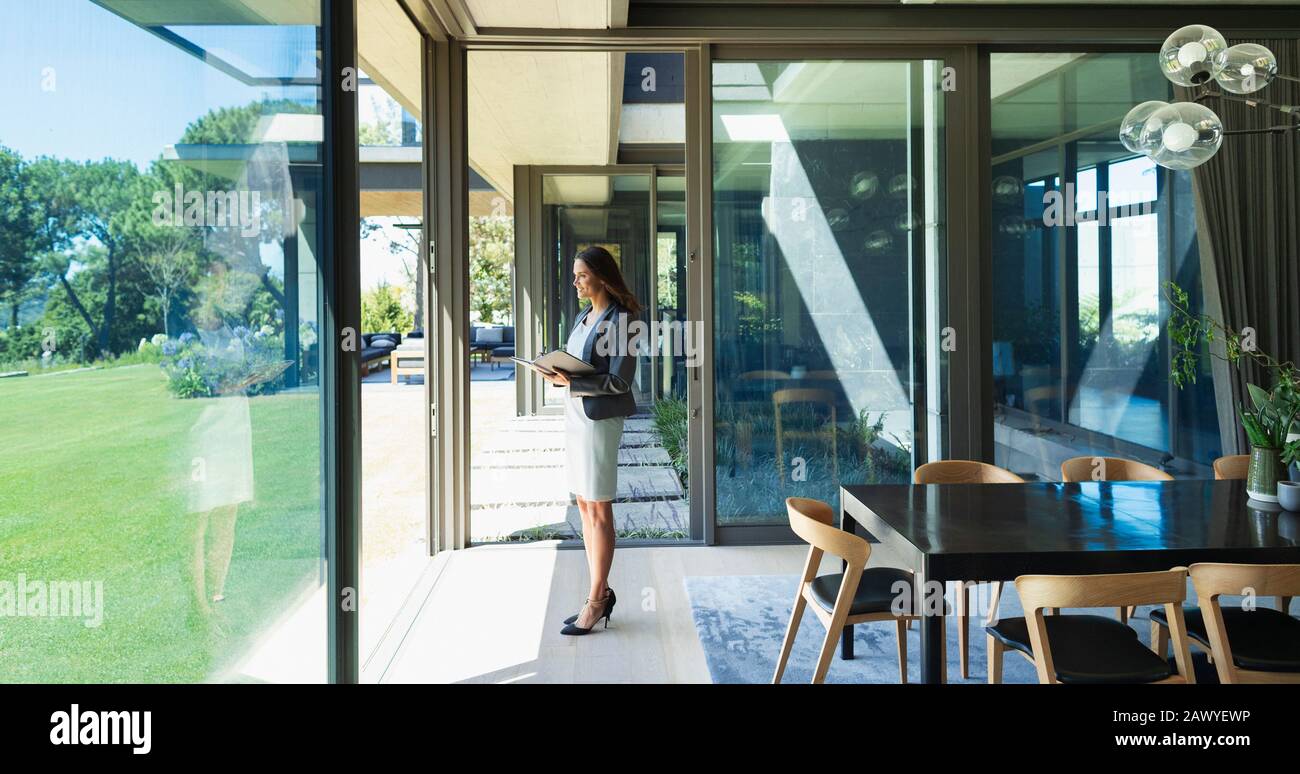 Selbstbewusste Geschäftsfrau, die von zu Hause aus arbeitet und auf dem Flur steht Stockfoto