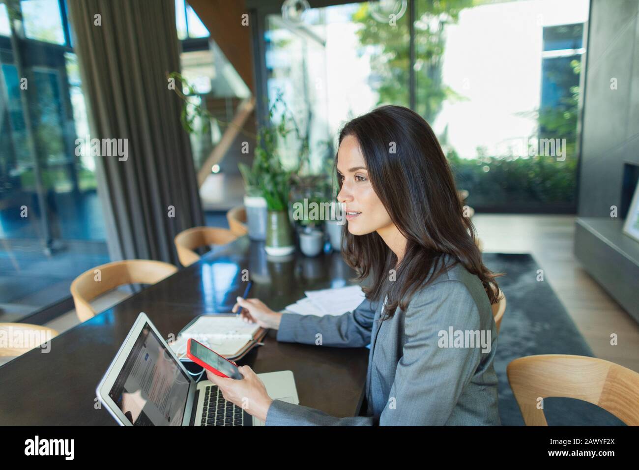 Geschäftsfrau, die von zu Hause aus mit Smartphone und Laptop arbeitet Stockfoto