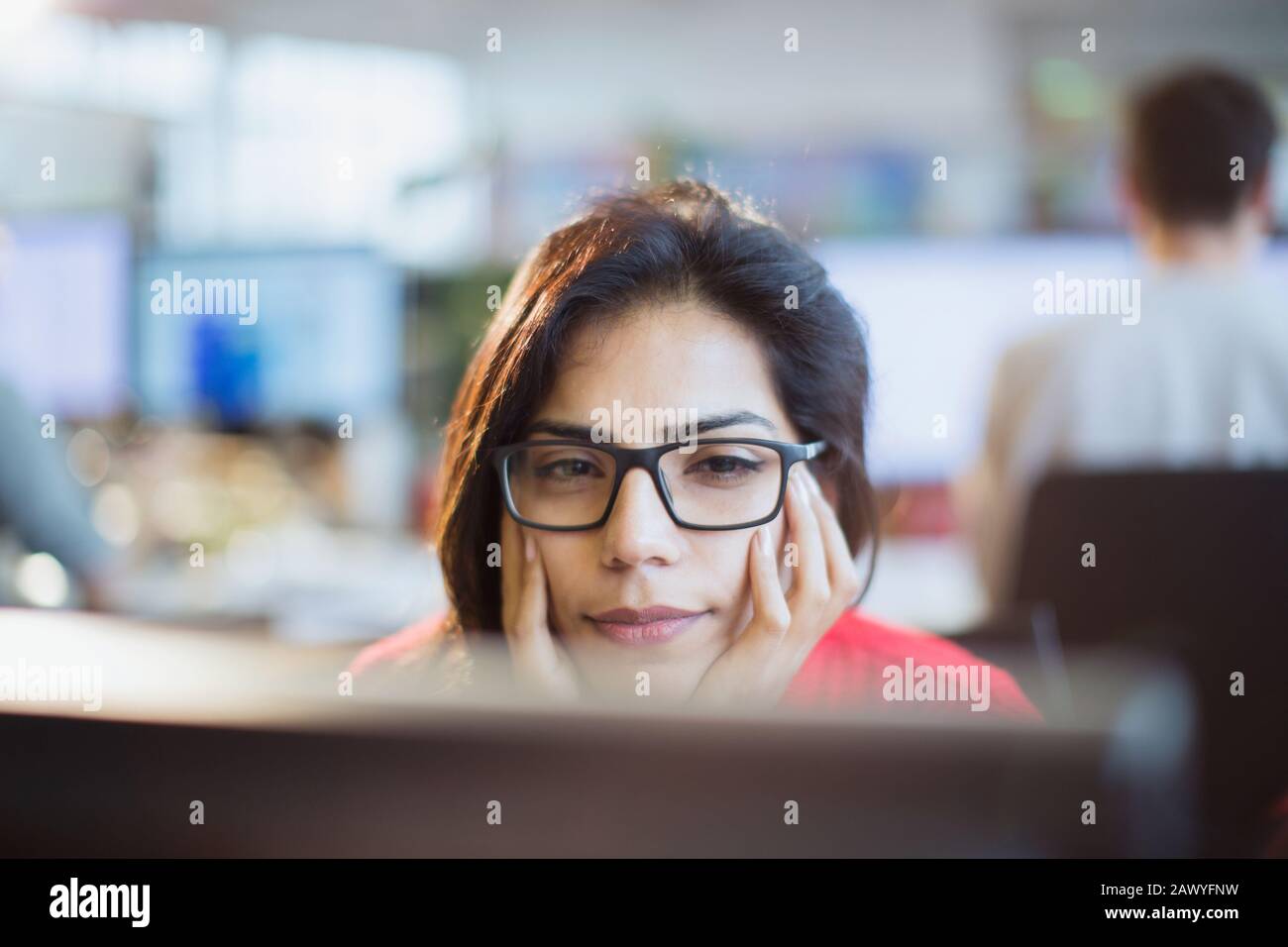 Fokussierte Geschäftsfrau mit einem Kopf in den Händen, die am Computer im Büro arbeitet Stockfoto