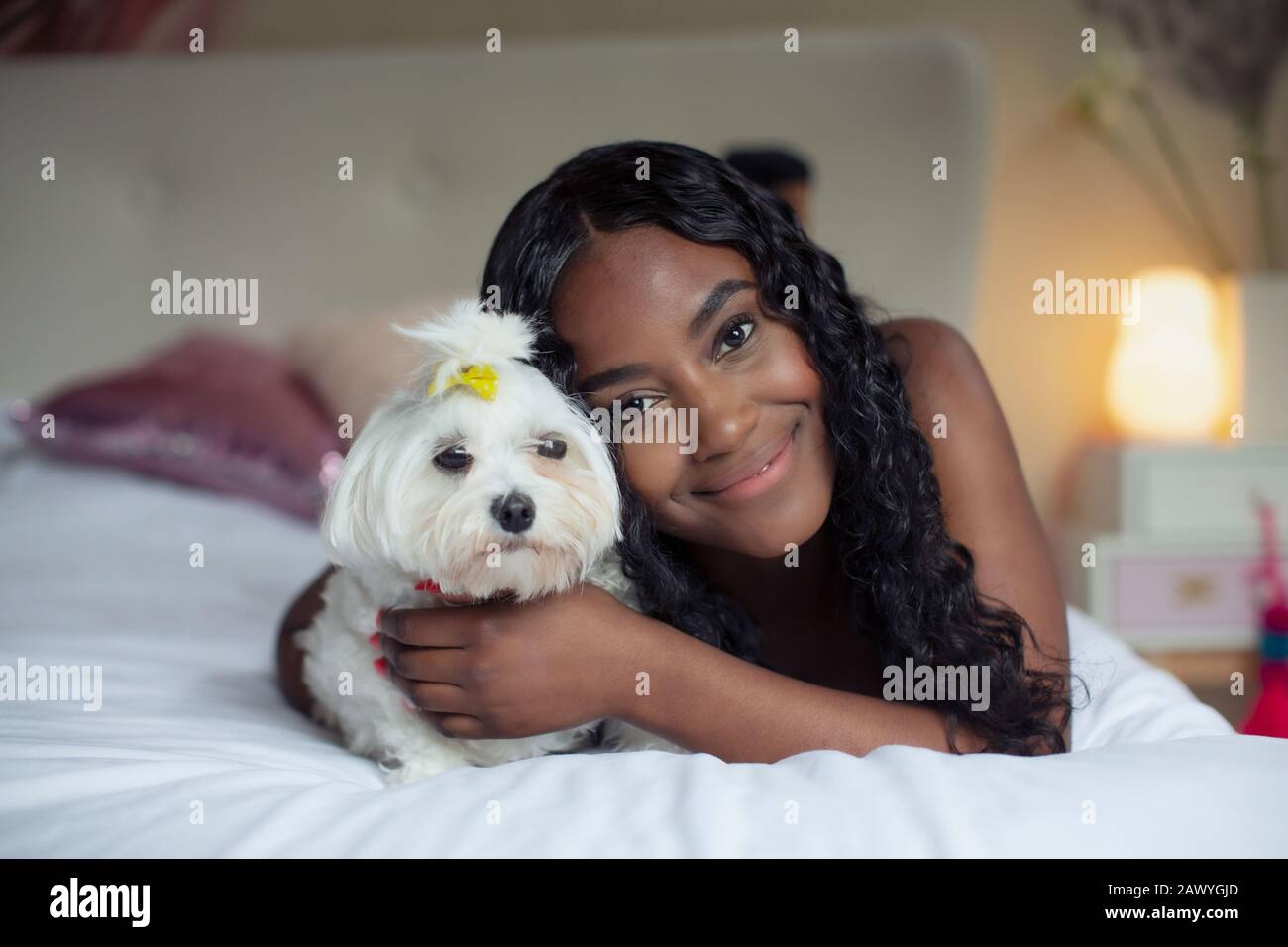Portrait fröhliche junge Frau mit Hund im Bett Stockfoto