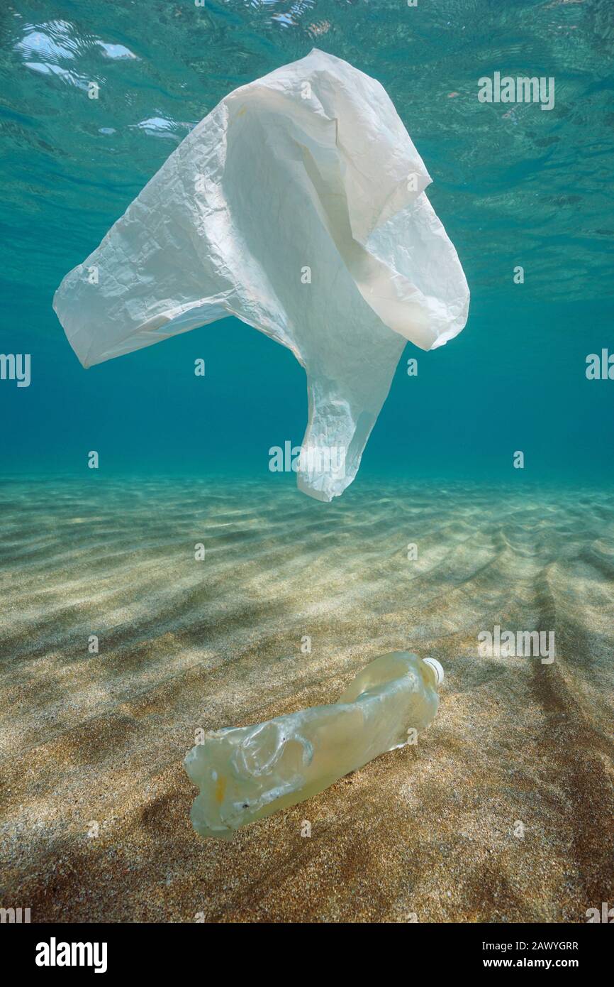 Plastische Verschmutzung im Meer unter Wasser, ein Plastikbeutel treibt und eine Flasche auf einem sandigen Meeresgrund im Mittelmeer, Frankreich Stockfoto