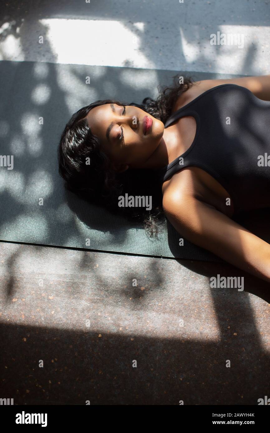 Heitere junge Frau legt auf Yogamatte Stockfoto