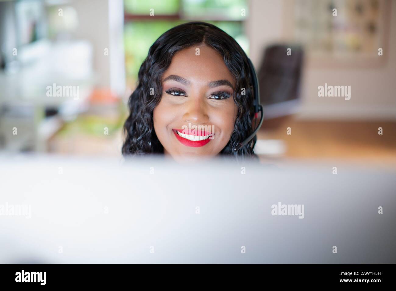 Portrait lächelnde junge Frau mit Headset, das am Computer arbeitet Stockfoto