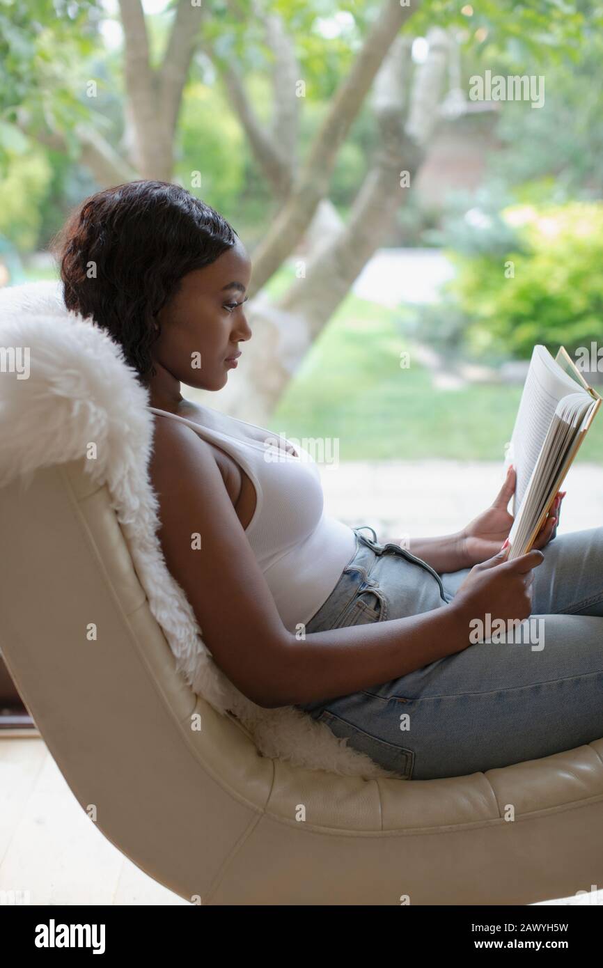 Junge Frau entspannendes Lesebuch im Wohnzimmer Stockfoto