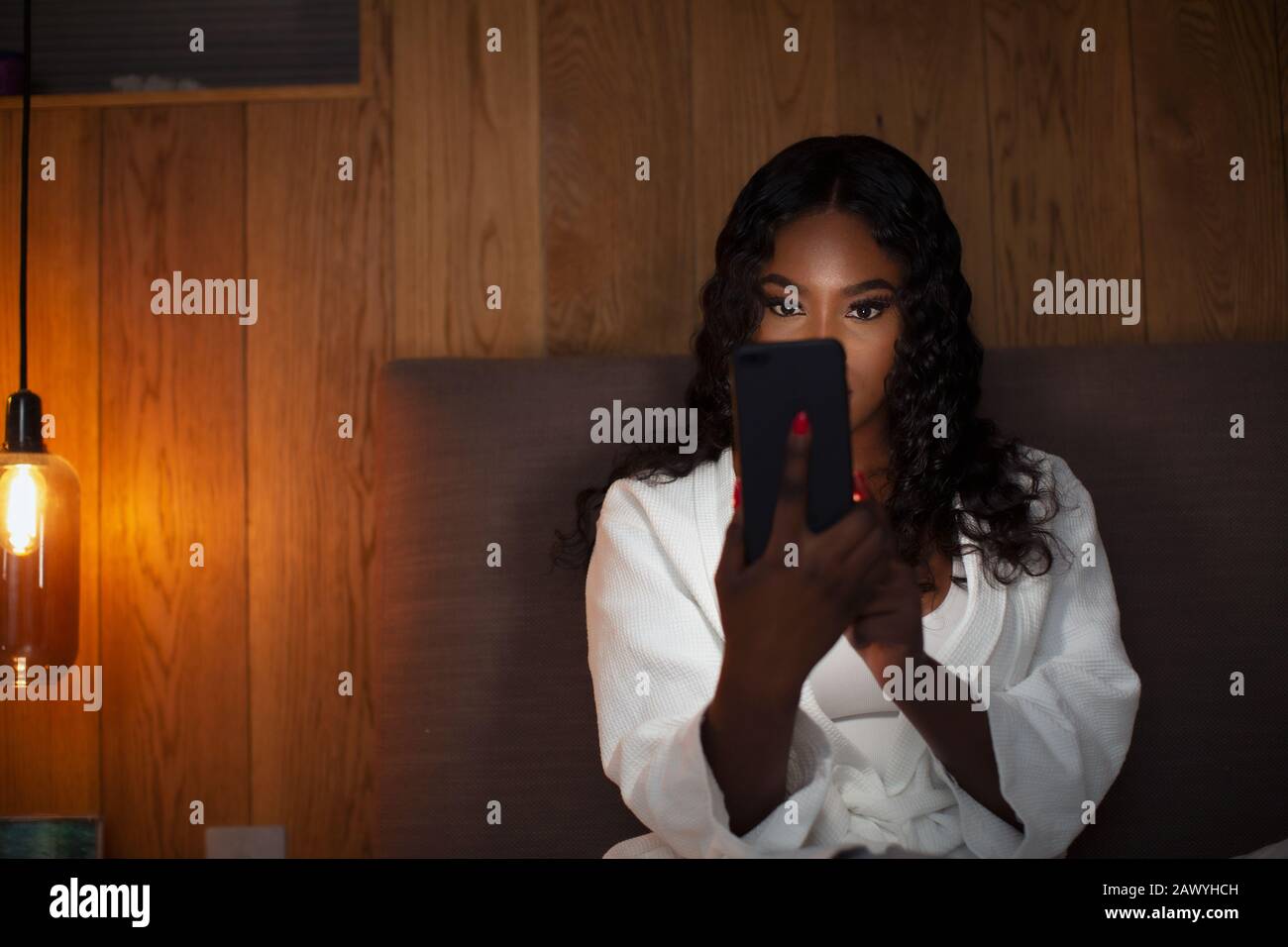 Junge Frau mit Smartphone im dunklen Schlafzimmer Stockfoto