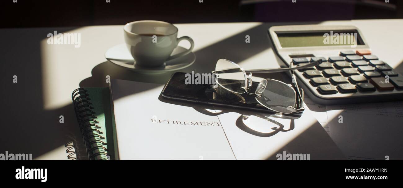 Altersvorsorge am sonnigen Schreibtisch mit Brille und Smartphone Stockfoto