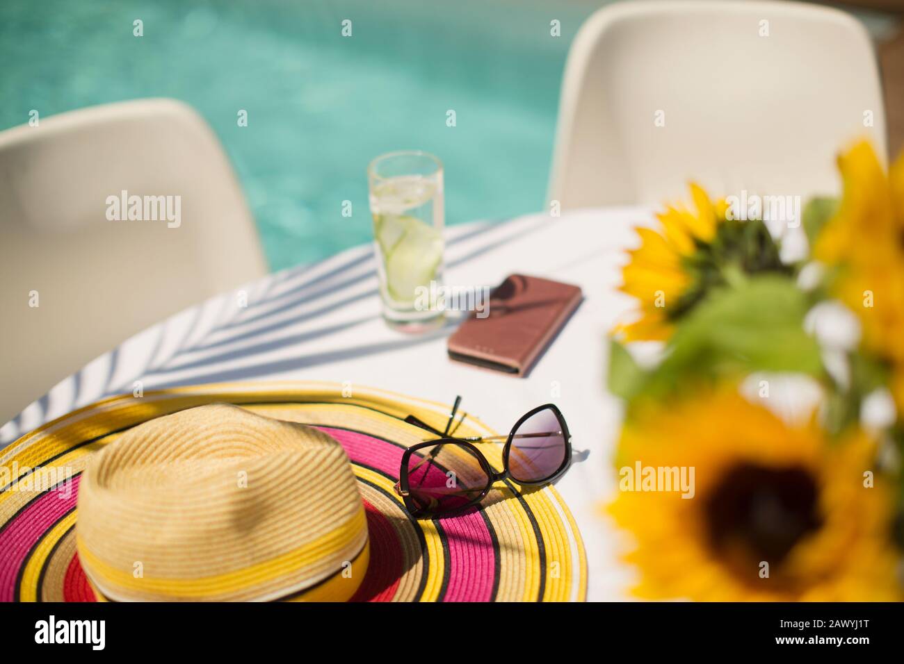Sonnenhut und Sonnenbrille am sonnigen Sommertisch am Pool Stockfoto