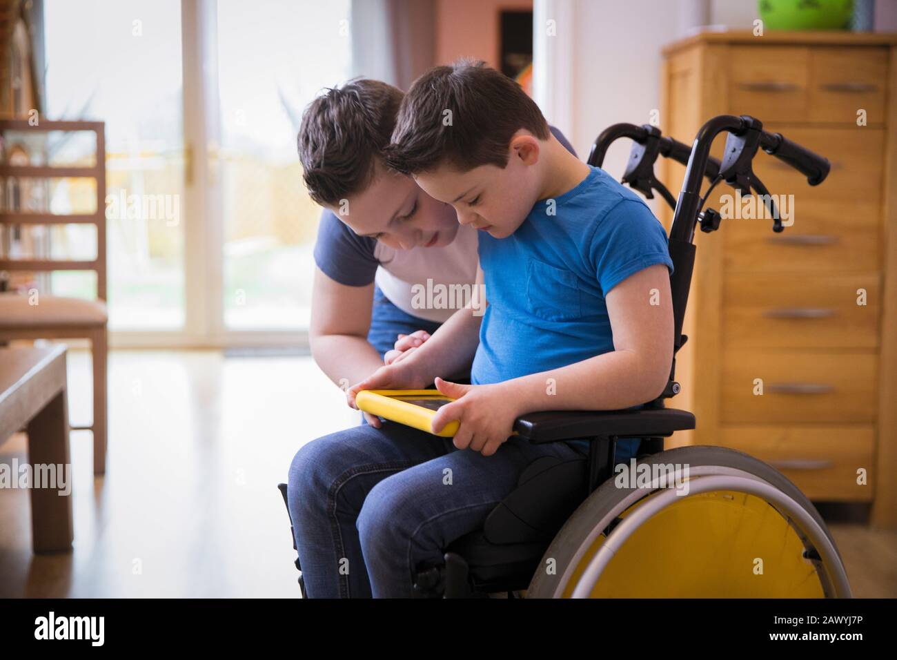 Junge mit Down-Syndrom mit digitaler Tablette im Rollstuhl Stockfoto