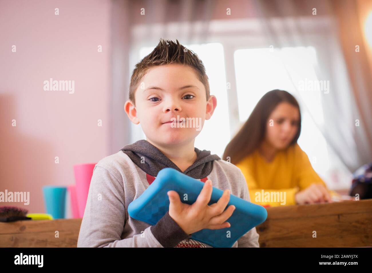 Portrait lächelnder Junge mit Down-Syndrom mit digitalem Tablet Stockfoto