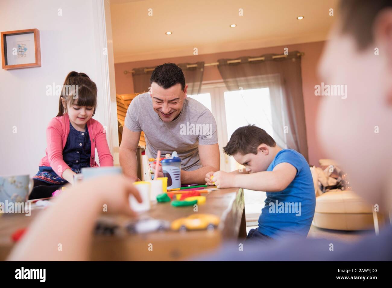 Glücklicher Vater, der mit Kindern am Esstisch spielt Stockfoto
