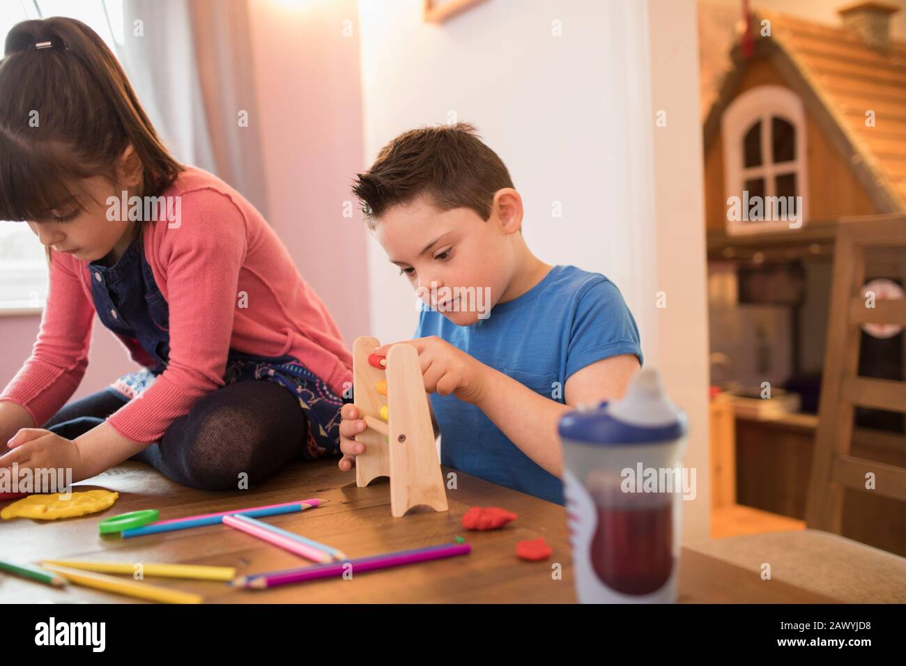 Fokussierter Junge mit Down-Syndrom, der mit Spielzeug am Tisch spielt Stockfoto
