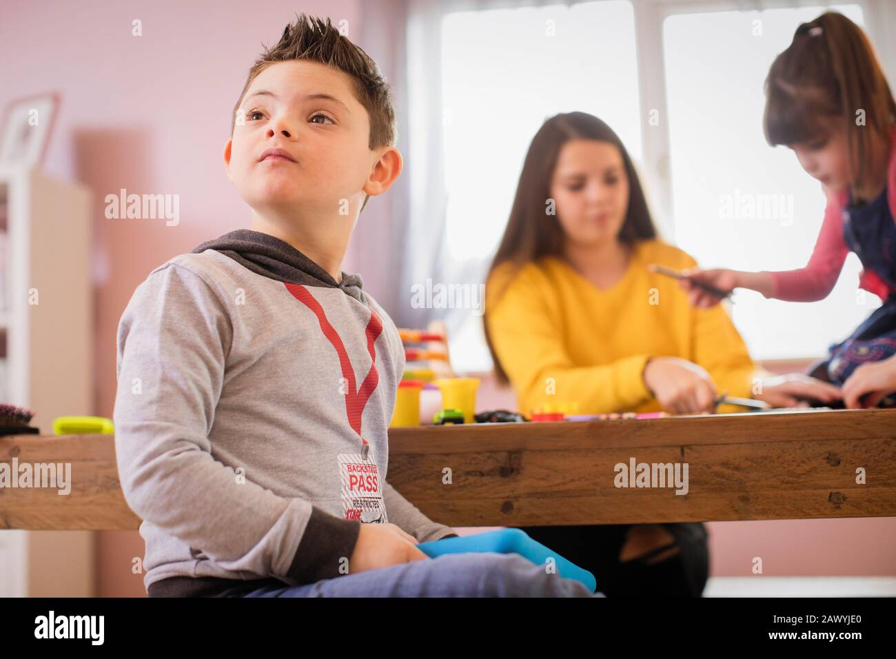 Neugieriger Junge mit Down-Syndrom, der am Tisch spielt Stockfoto