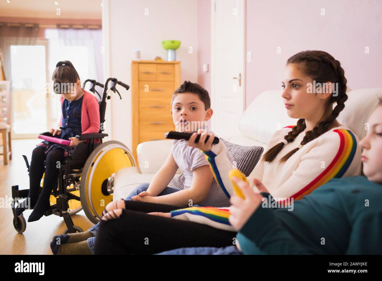 Portrait Junge mit Daon-Syndrom Fernsehen mit Familie auf Sofa Stockfoto
