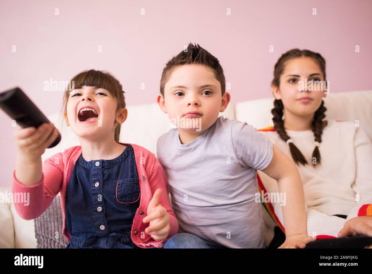 Schwestern und Bruder mit Down-Syndrom Fernsehen auf dem Sofa Stockfoto