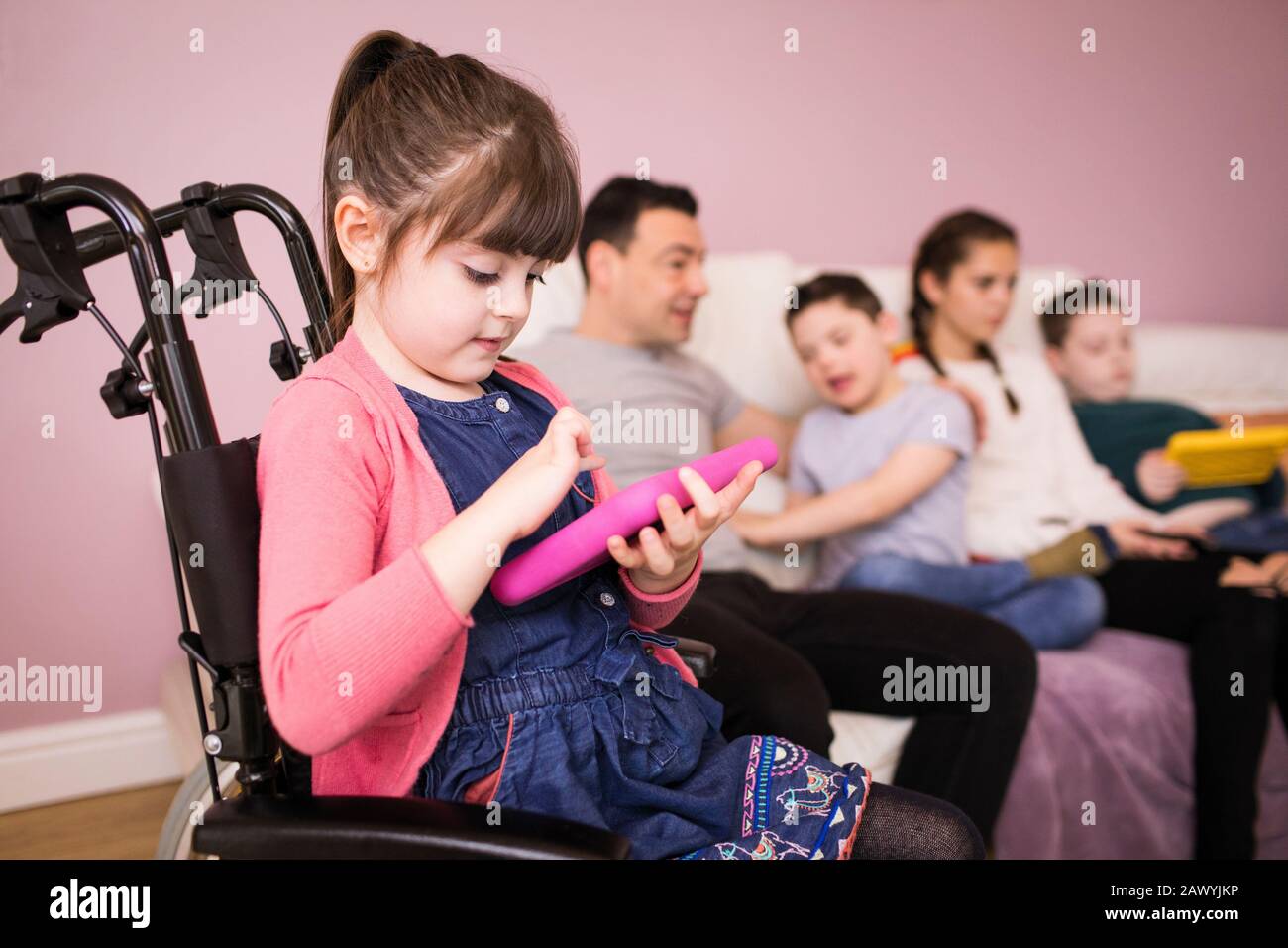 Mädchen, die ein digitales Tablet im Rollstuhl verwenden Stockfoto