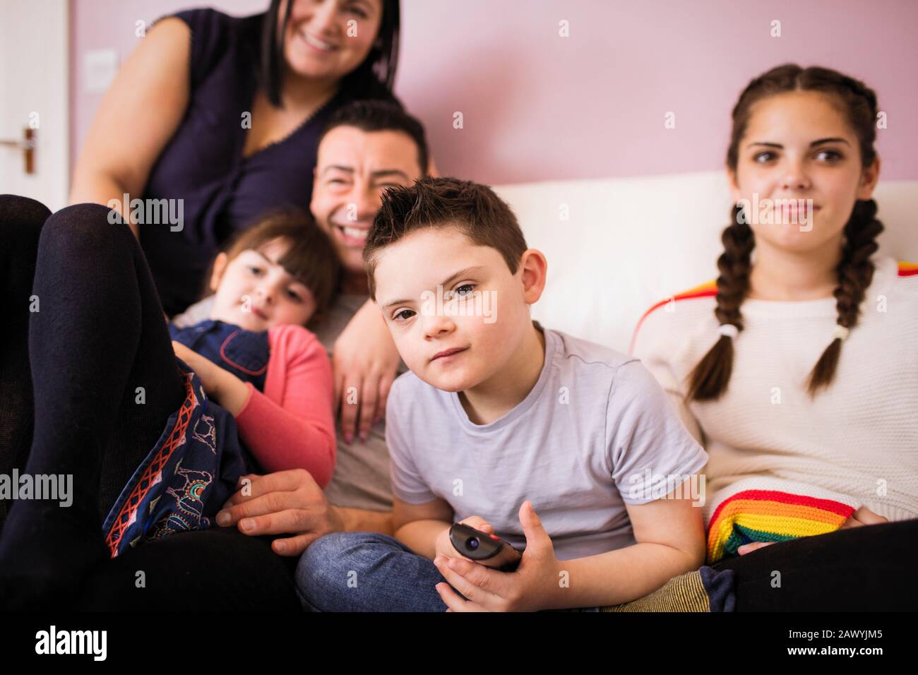 Portrait Junge mit Daon-Syndrom Fernsehen mit Familie auf Sofa Stockfoto