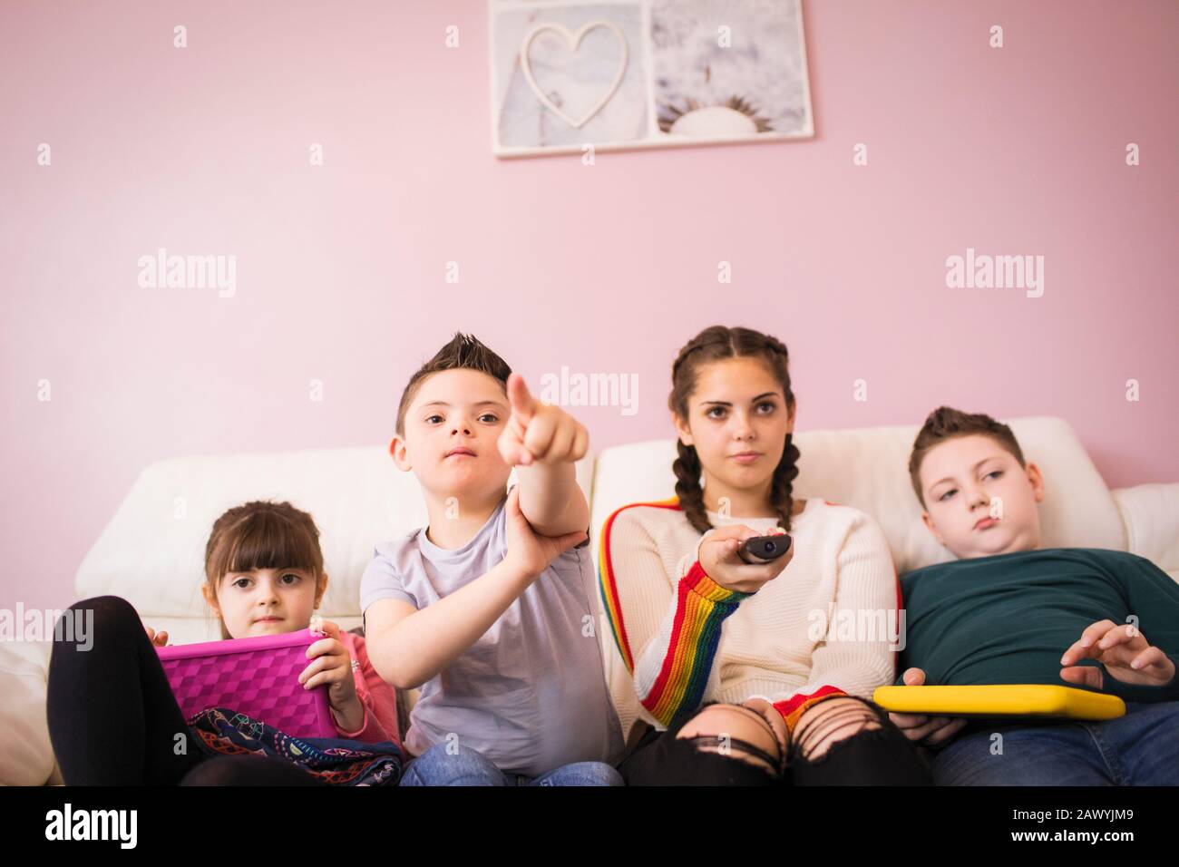 Down Syndrome Junge Fernsehen mit Geschwistern auf dem Sofa Stockfoto