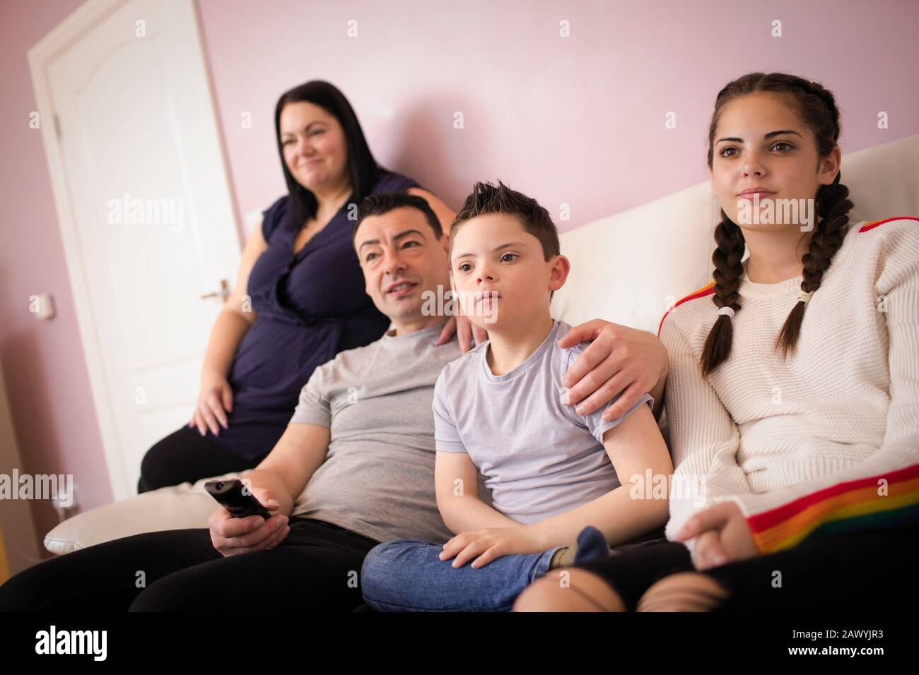 Familie mit Daon-Syndrom-Sohn, die Fernsehen auf dem Sofa im Wohnzimmer sieht Stockfoto