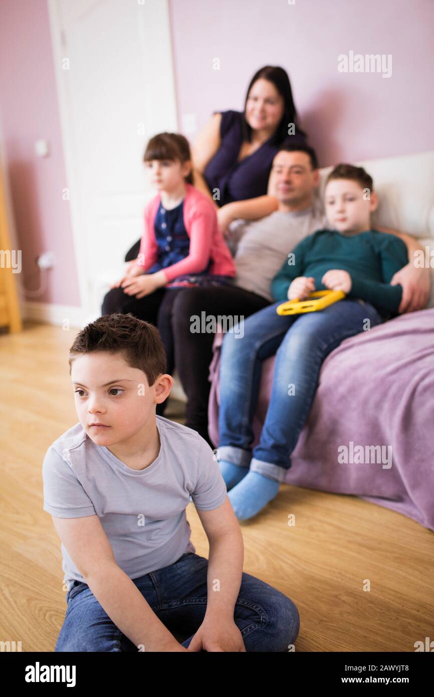 Junge mit Down-Syndrom Fernsehen mit Familie im Wohnzimmer Stockfoto