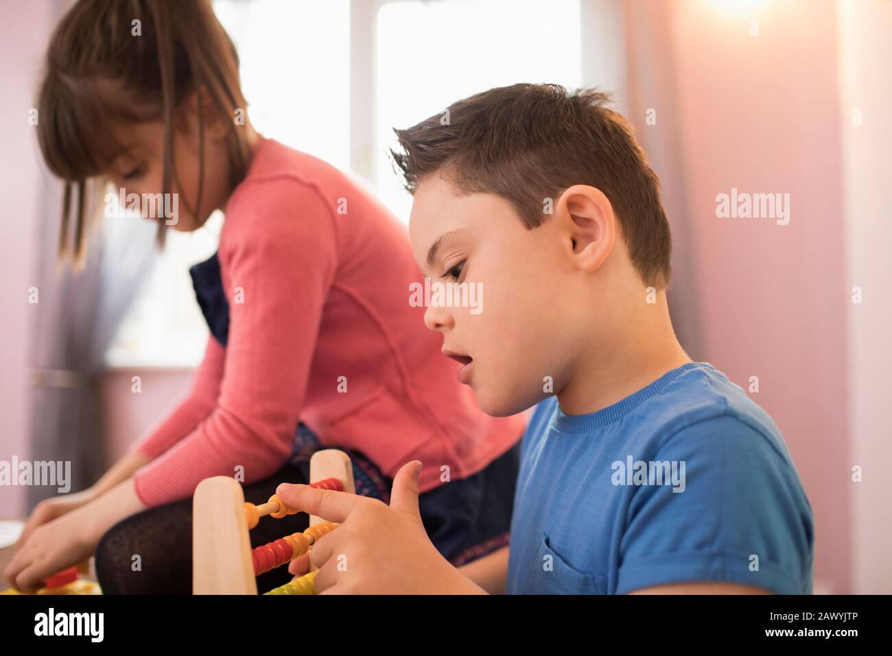 Neugieriger Junge mit Down-Syndrom, der mit Spielzeug spielt Stockfoto